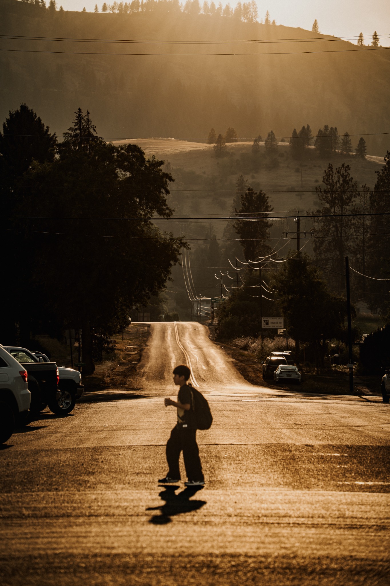 A boy crossing a street beneath layered Idaho mountains