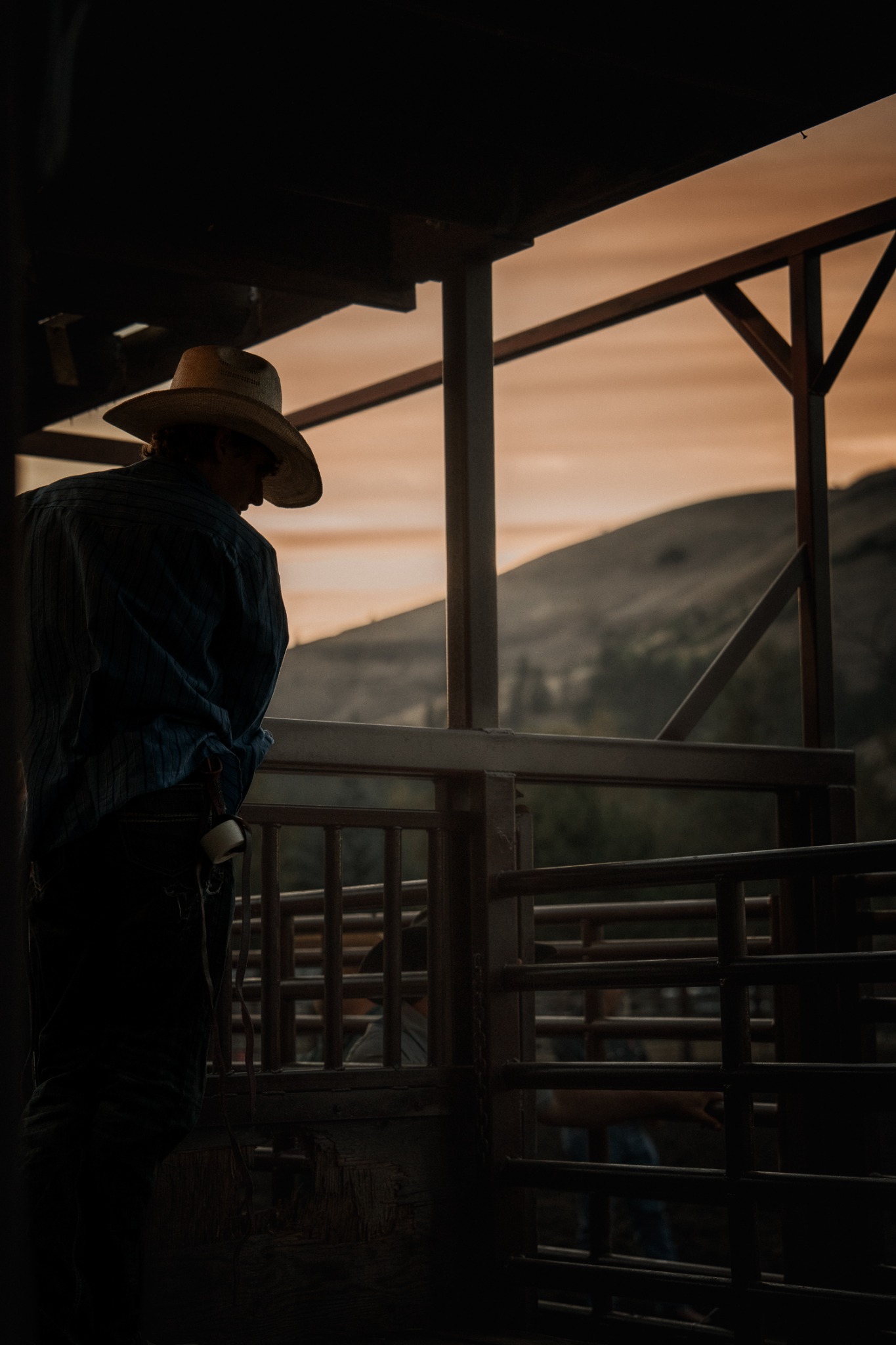 A cowboy watching the arena at dusk